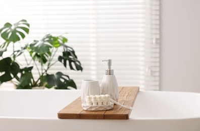 Photo of Set of different bath accessories and soap on tub in bathroom