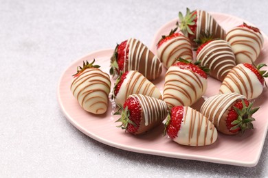 Photo of Heart shaped plate with delicious chocolate covered strawberries on light table, closeup