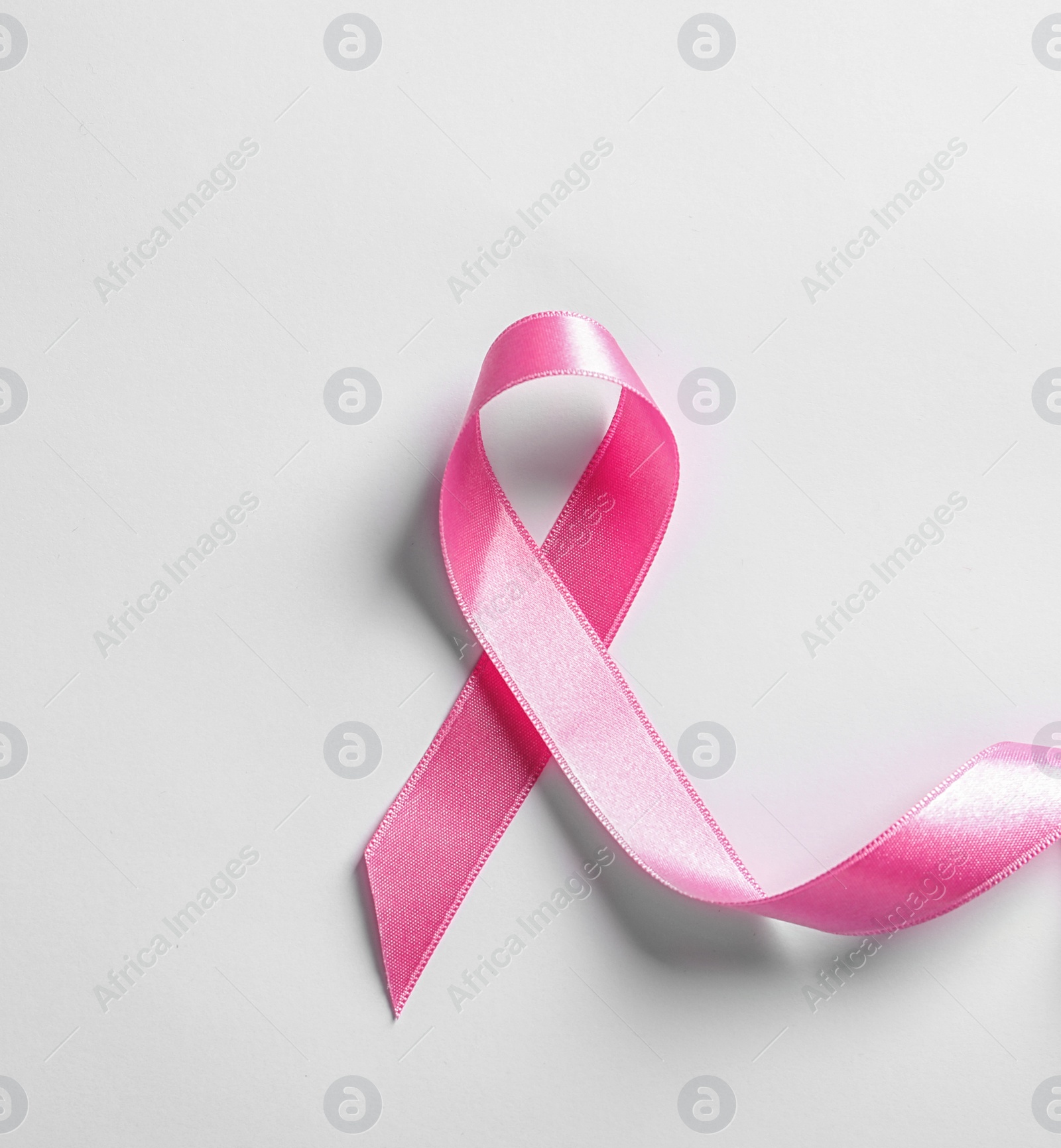 Photo of Pink ribbon on white background, top view. Cancer awareness