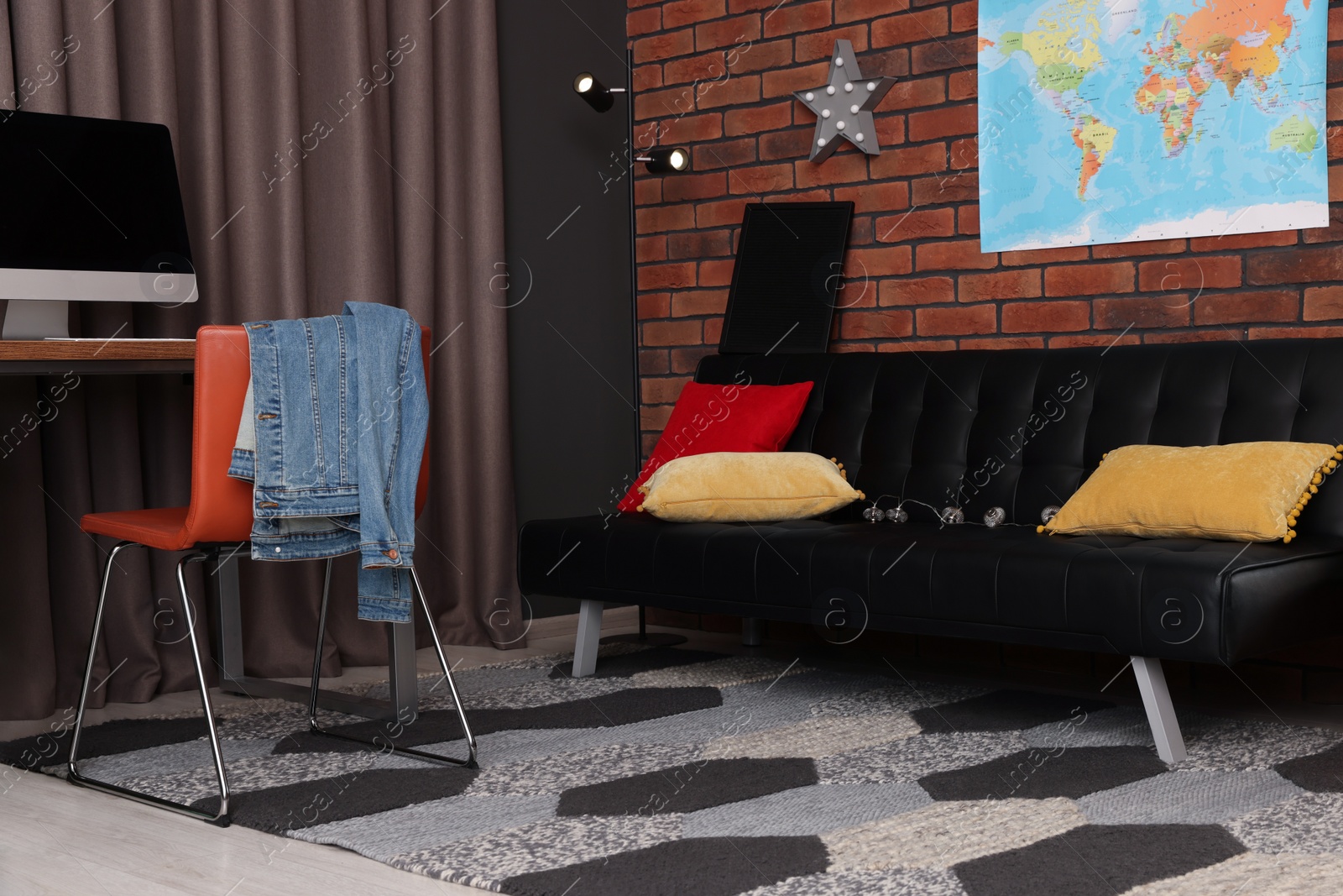 Photo of Stylish teenager's room with computer, black sofa and world map on brick wall