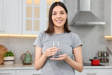 Photo of Woman with glass of fresh water in kitchen