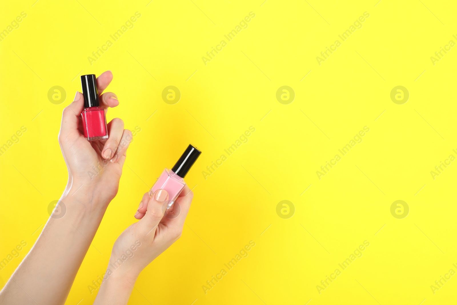 Photo of Woman holding nail polishes on yellow background, closeup. Space for text