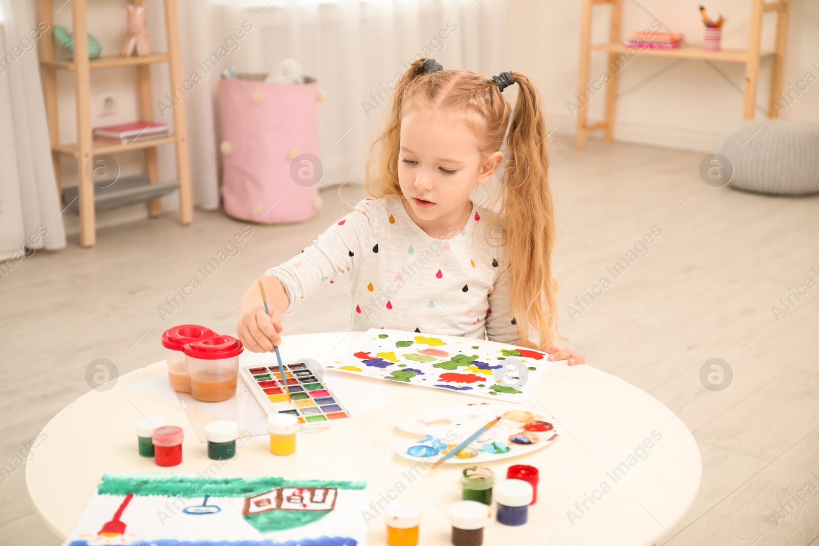 Photo of Cute little child painting at table in room