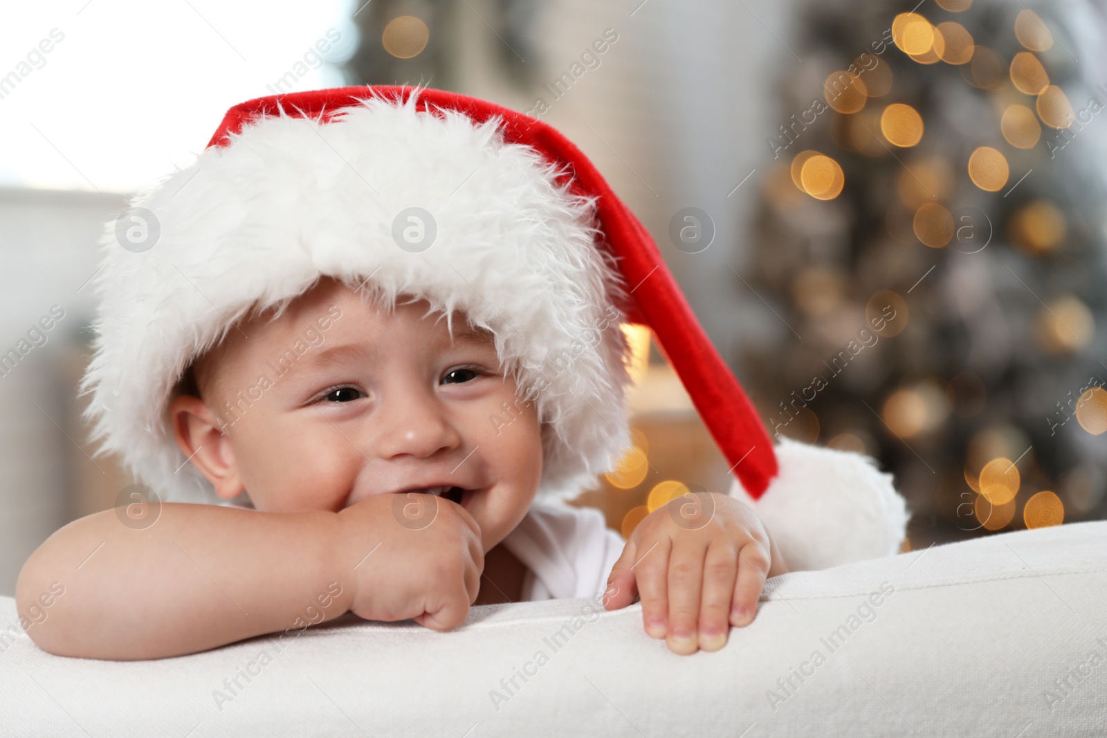 Image of Cute little baby wearing Santa hat at home. Christmas celebration