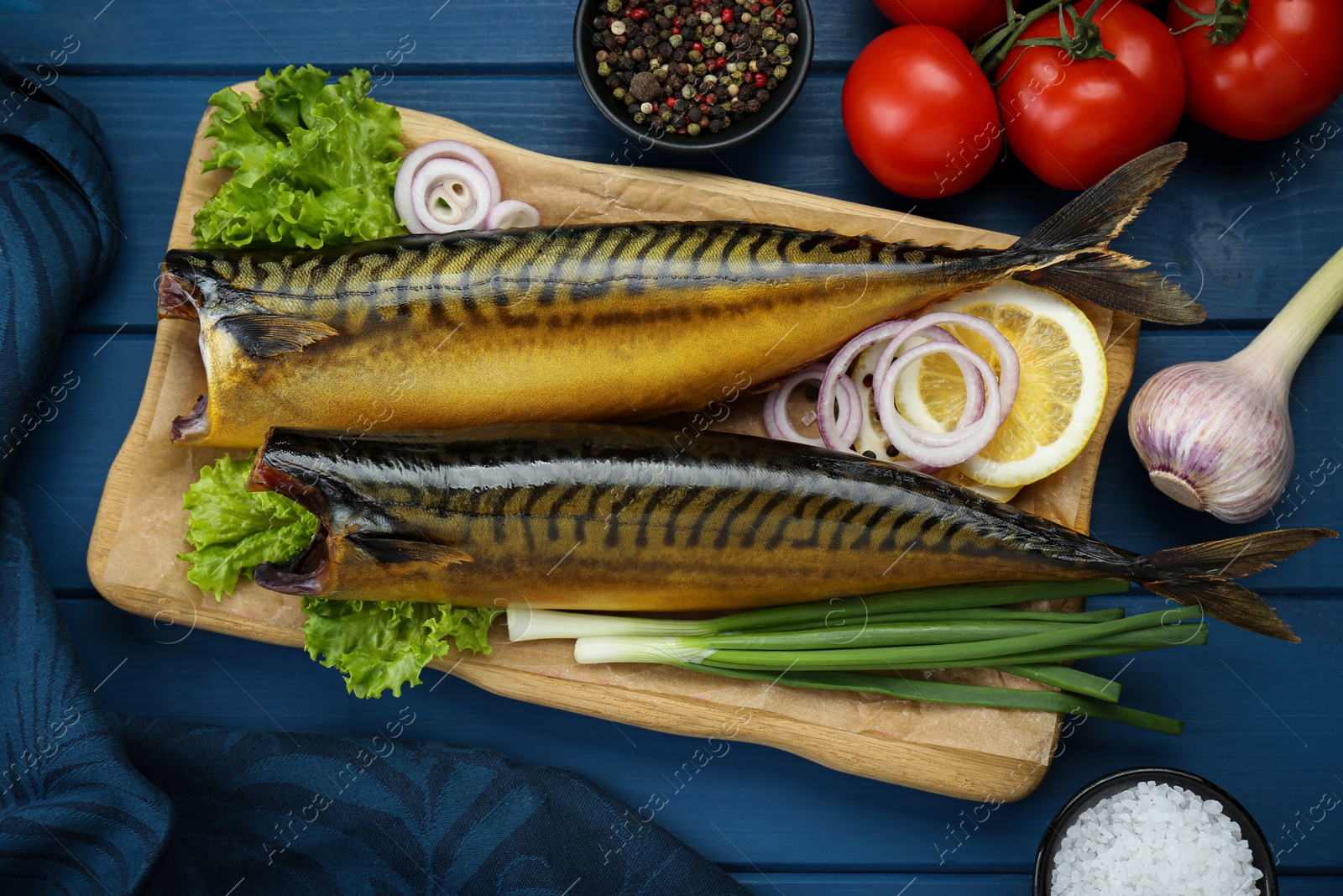 Photo of Delicious smoked mackerels and products on blue wooden table, flat lay