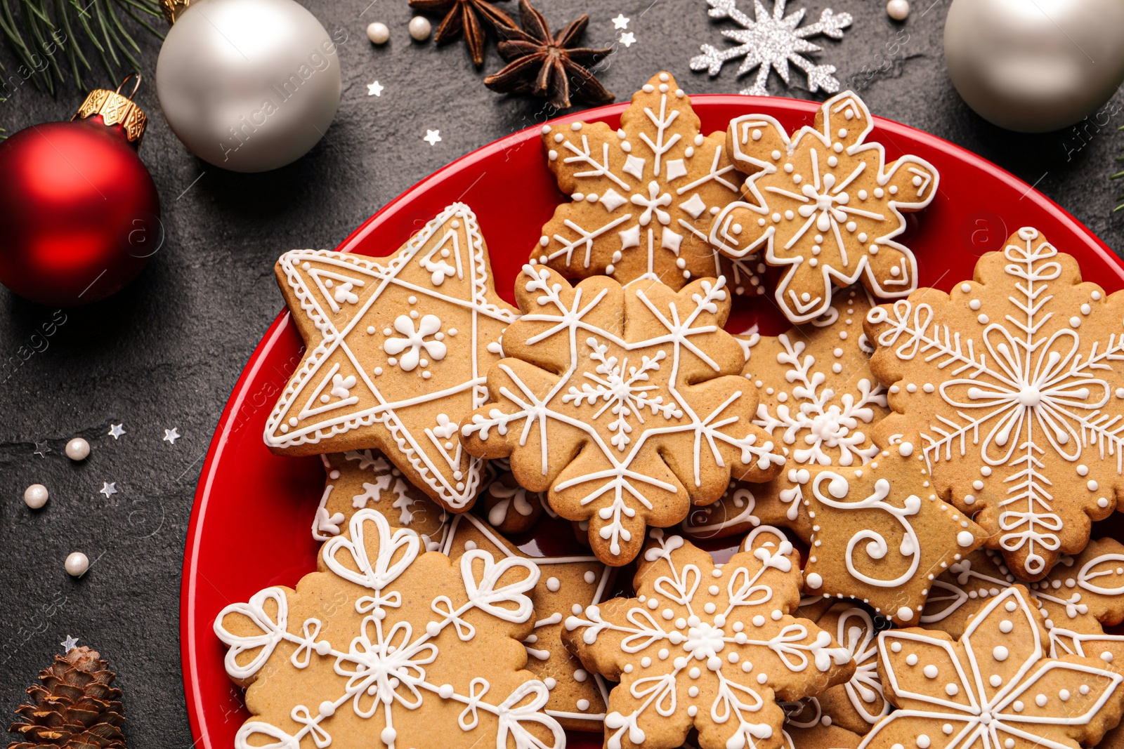 Photo of Tasty Christmas cookies, fir branches and festive decor on black table, flat lay