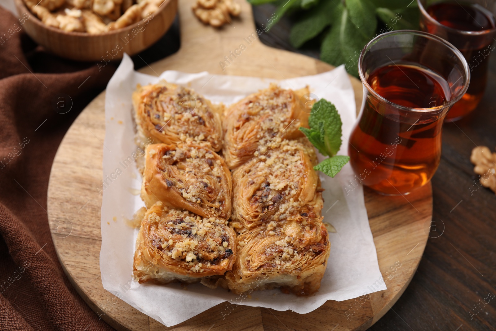 Photo of Eastern sweets. Pieces of tasty baklava and tea on wooden table, closeup