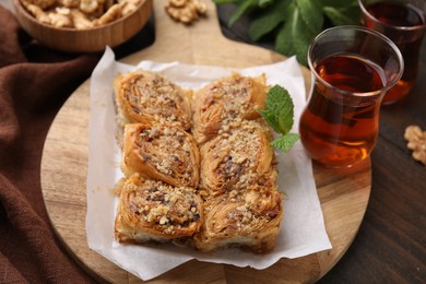 Photo of Eastern sweets. Pieces of tasty baklava and tea on wooden table, closeup