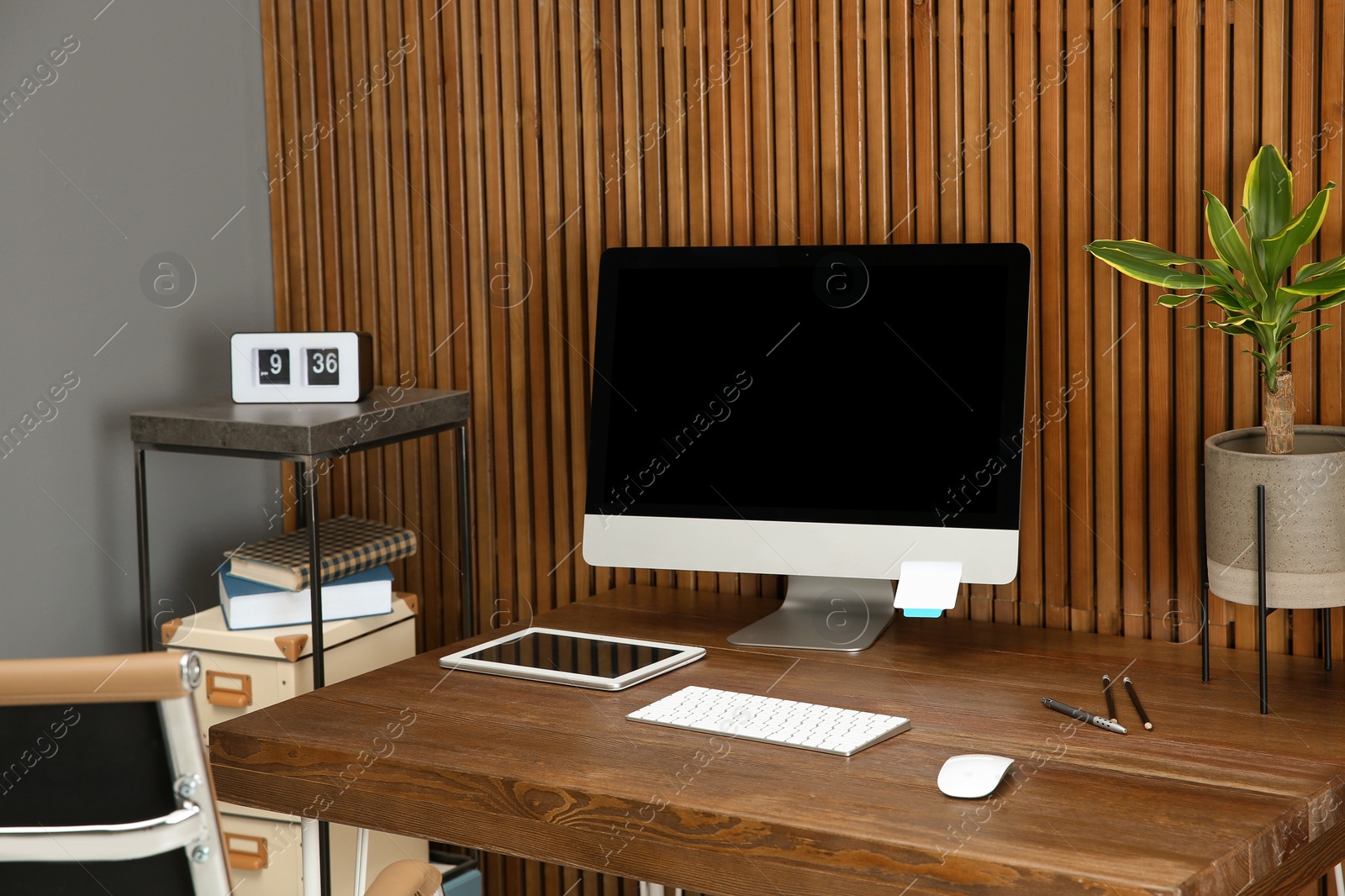 Photo of Stylish workplace with modern computer near wooden wall. Space for text