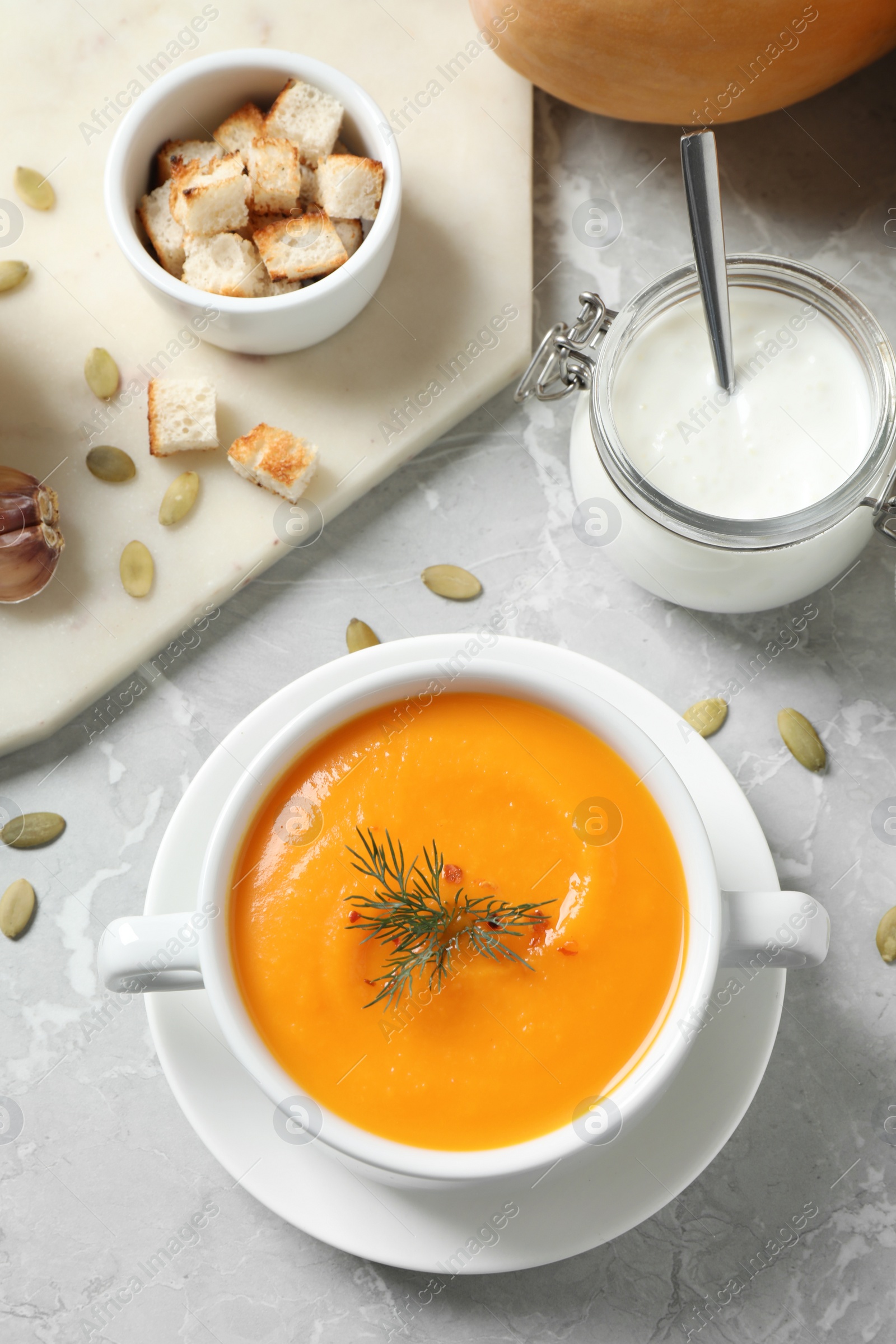 Photo of Delicious pumpkin soup in bowl on marble table, flat lay