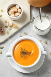 Photo of Delicious pumpkin soup in bowl on marble table, flat lay