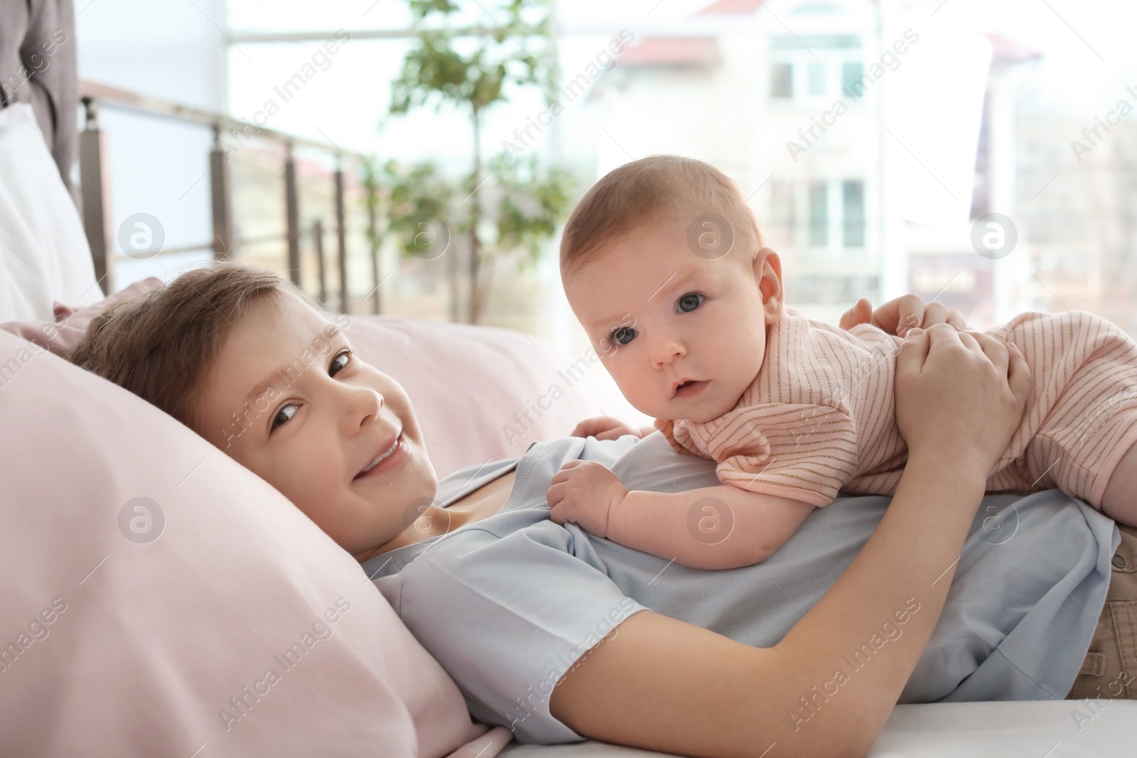 Photo of Cute little baby with elder brother lying on bed at home