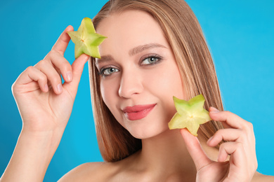 Photo of Young woman with cut carambola on blue background. Vitamin rich food