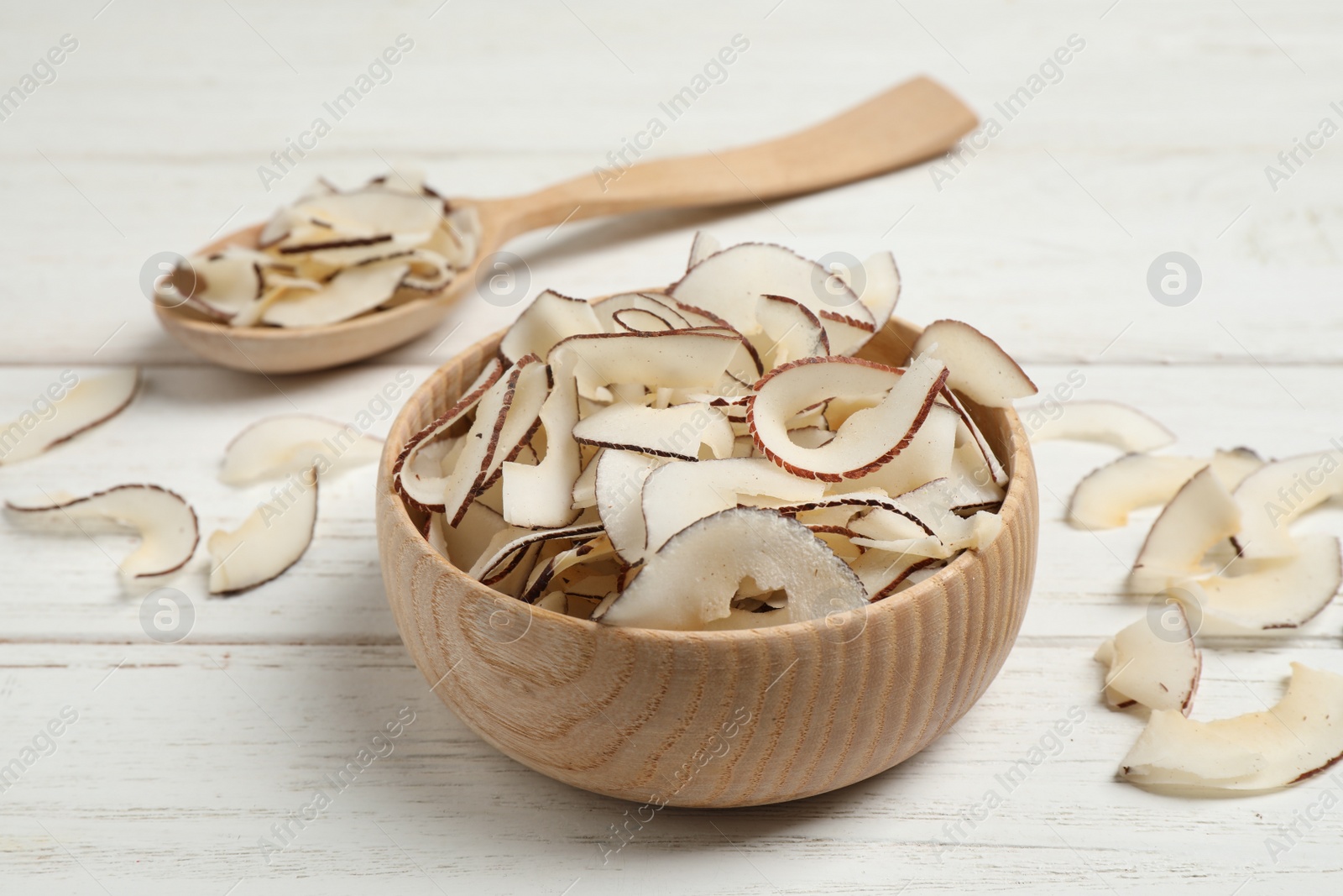 Photo of Tasty coconut chips on white wooden table