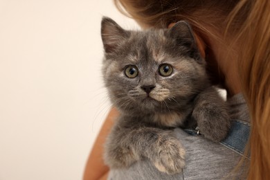 Photo of Cute little girl holding kitten on light background, closeup with space for text. Childhood pet