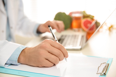 Photo of Nutritionist working at desk in office, closeup