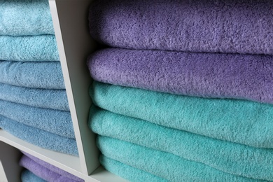 Photo of Colorful towels on shelves, closeup. Bathroom supplies