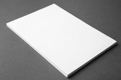 Photo of Blank paper sheets on dark grey background, closeup. Mock up for design