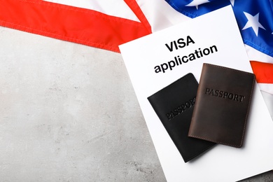 Photo of Flat lay composition with flag of USA, passports and visa application on gray background. Space for text