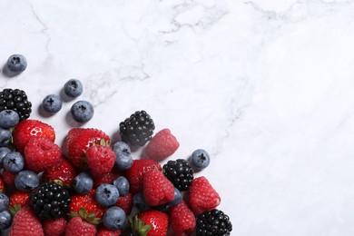 Photo of Many different fresh ripe berries on white marble table, flat lay. Space for text