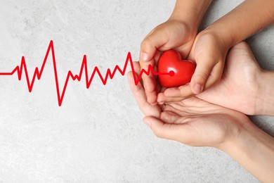 Woman and child holding heart on grey stone background, top view