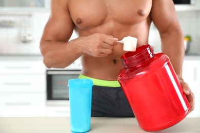 Photo of Young athletic man preparing protein shake in kitchen, closeup view