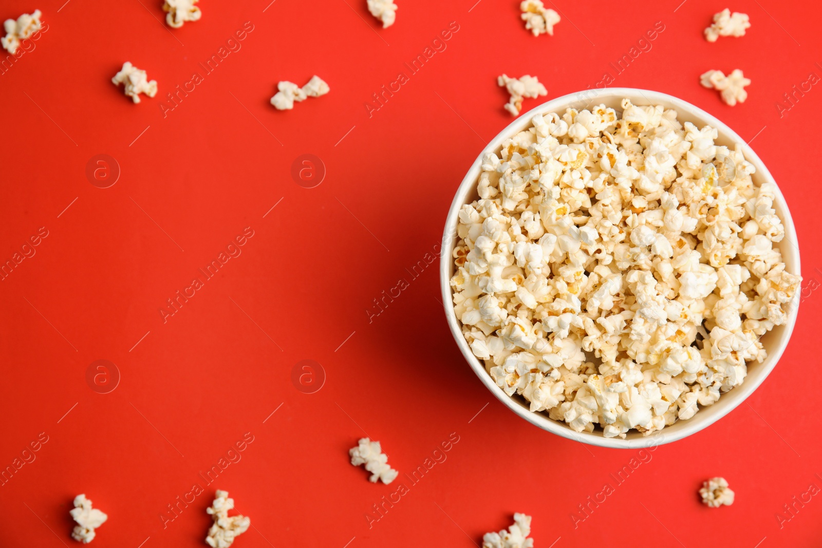 Photo of Tasty pop corn on red background, flat lay. Space for text