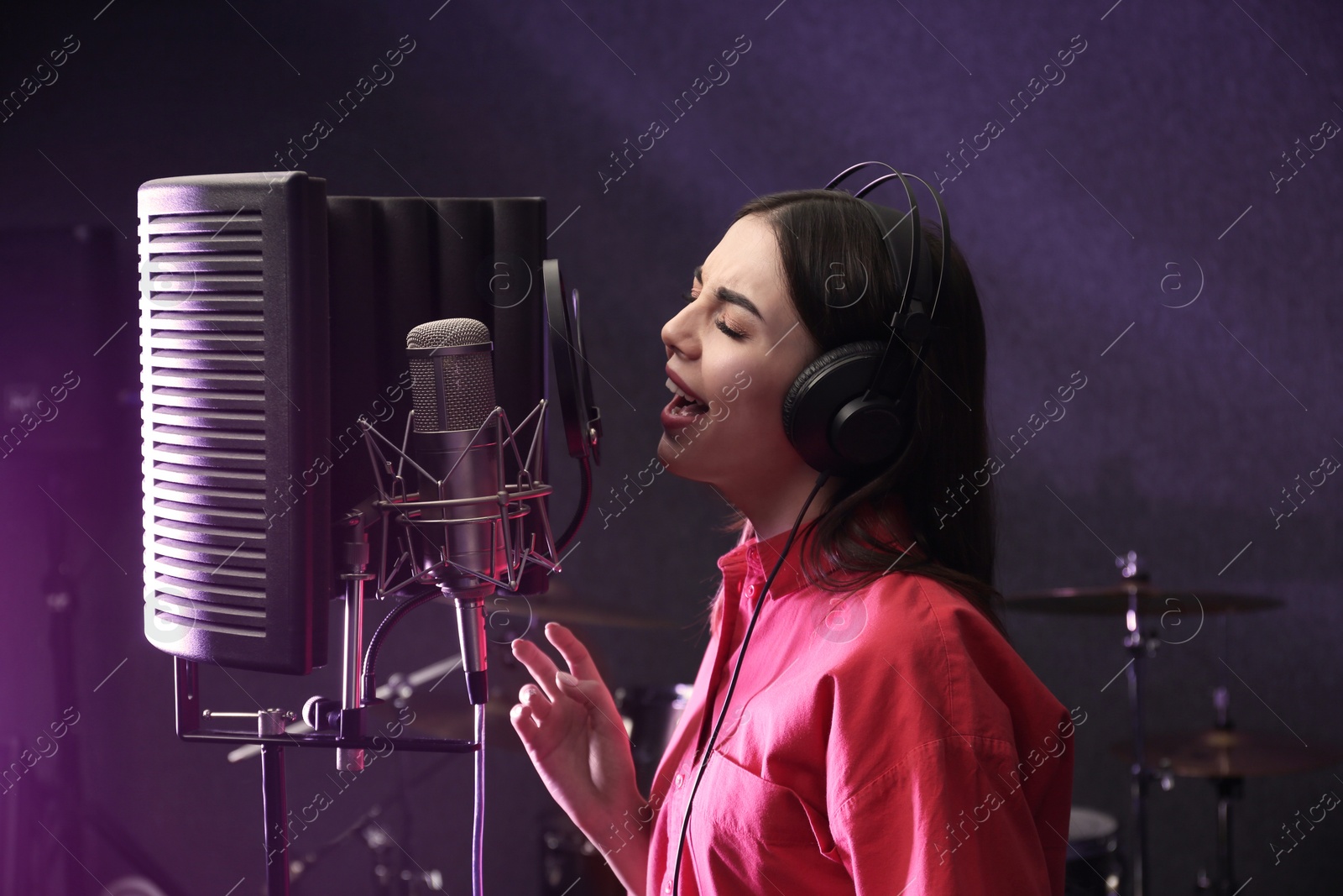 Photo of Young singer with microphone recording song in studio