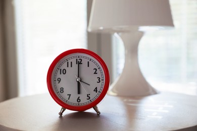 Photo of Red alarm clock on table indoors. Space for text