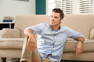 Photo of Man listening to audiobook near sofa at home