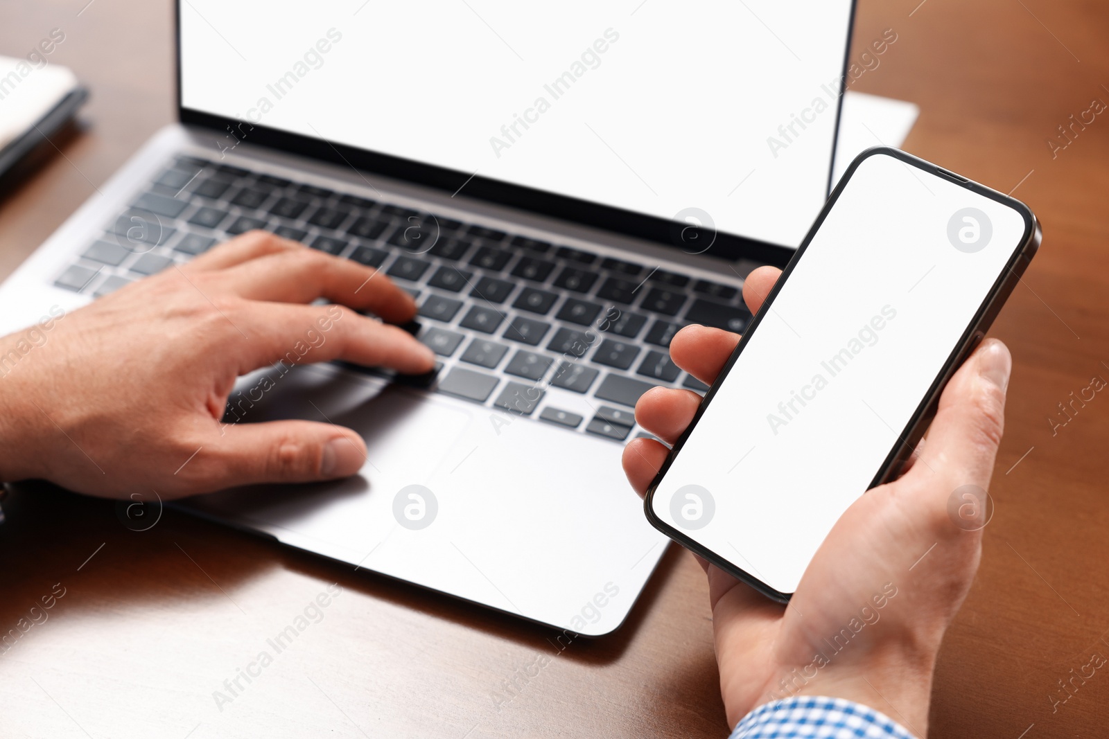 Photo of Man using smartphone and laptop at table, closeup