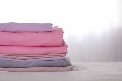 Photo of Stack of clean color folded linens on bed. Space for text