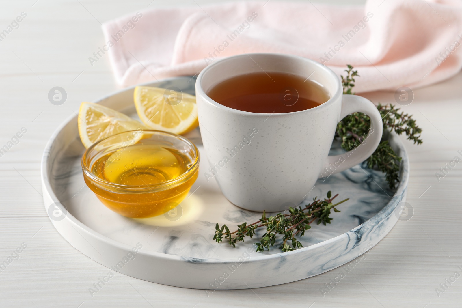 Photo of Aromatic herbal tea with thyme, honey and lemons on white wooden table