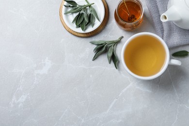 Photo of Flat lay composition with aromatic sage tea on light grey table. Space for text