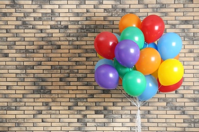 Photo of Bunch of bright balloons and space for text against brick wall