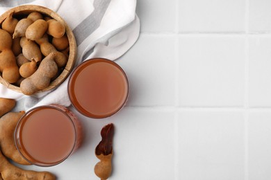 Tamarind juice and fresh fruits on white tiled table, flat lay. Space for text