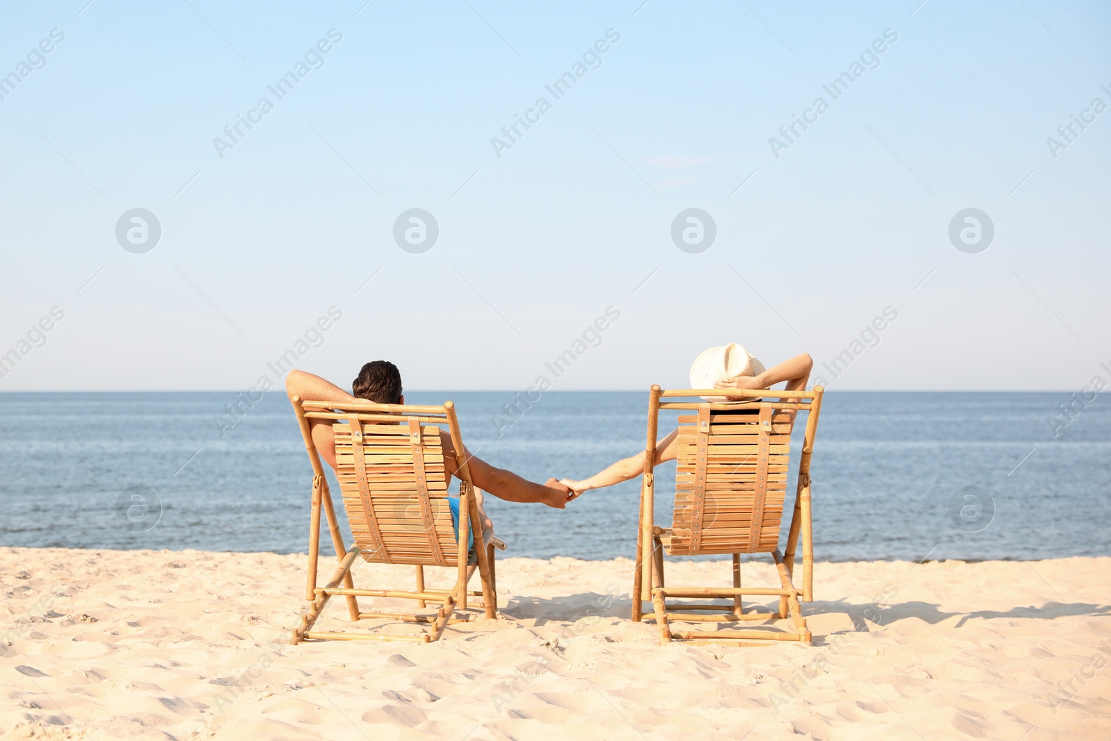 Photo of Couple resting on sunny beach at resort. Space for text