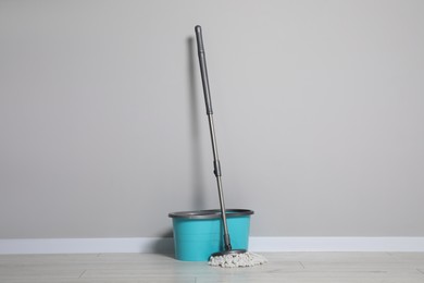 Photo of Mop and plastic bucket indoors. Cleaning floor