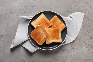 Photo of Plate with slices of delicious toasted bread on gray table, top view
