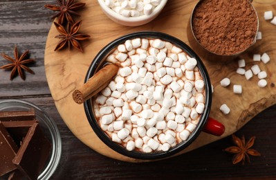 Photo of Tasty hot chocolate with marshmallows and ingredients on wooden table, flat lay