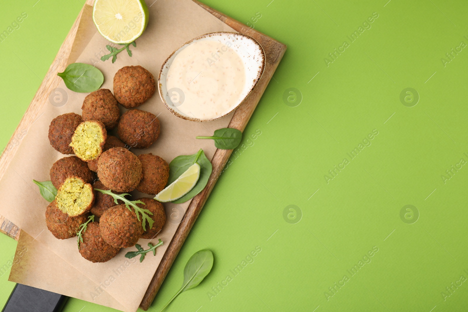 Photo of Delicious falafel balls served on green background, top view. Space for text
