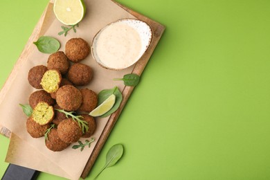 Delicious falafel balls served on green background, top view. Space for text