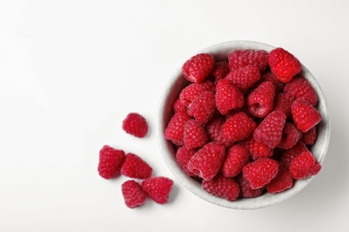 Bowl of delicious ripe raspberries on white background, top view