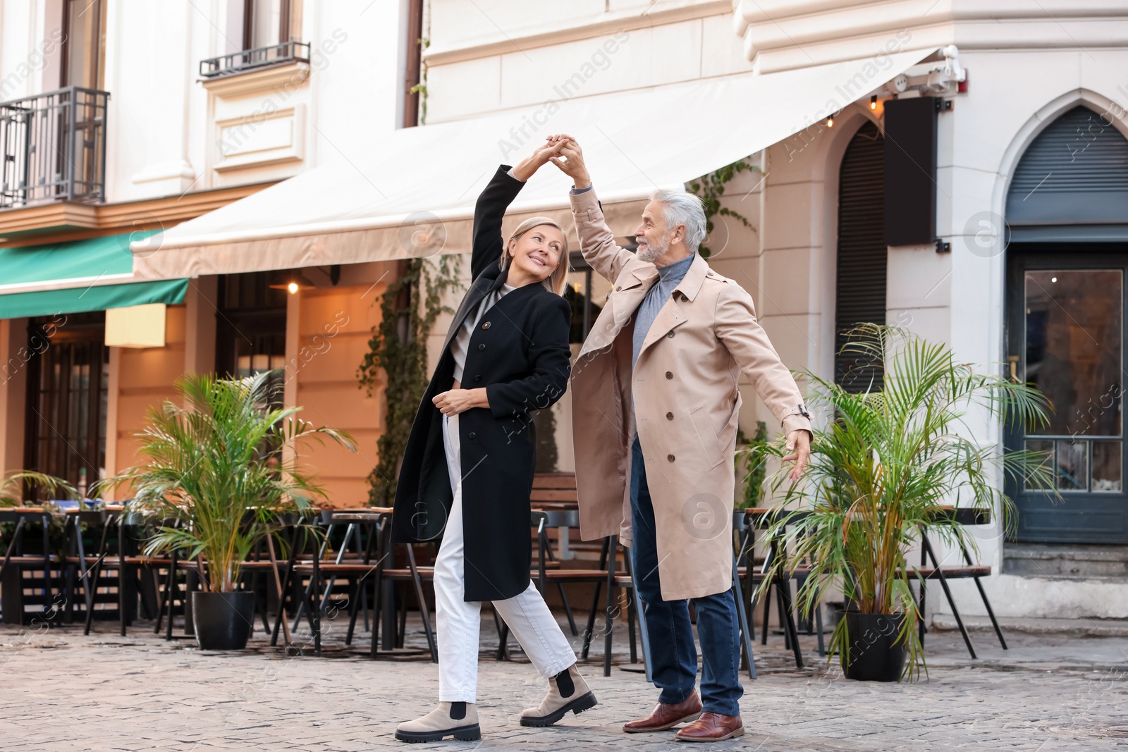 Photo of Affectionate senior couple dancing together on city street