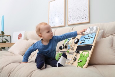 Photo of Cute little boy playing with busy board on sofa at home