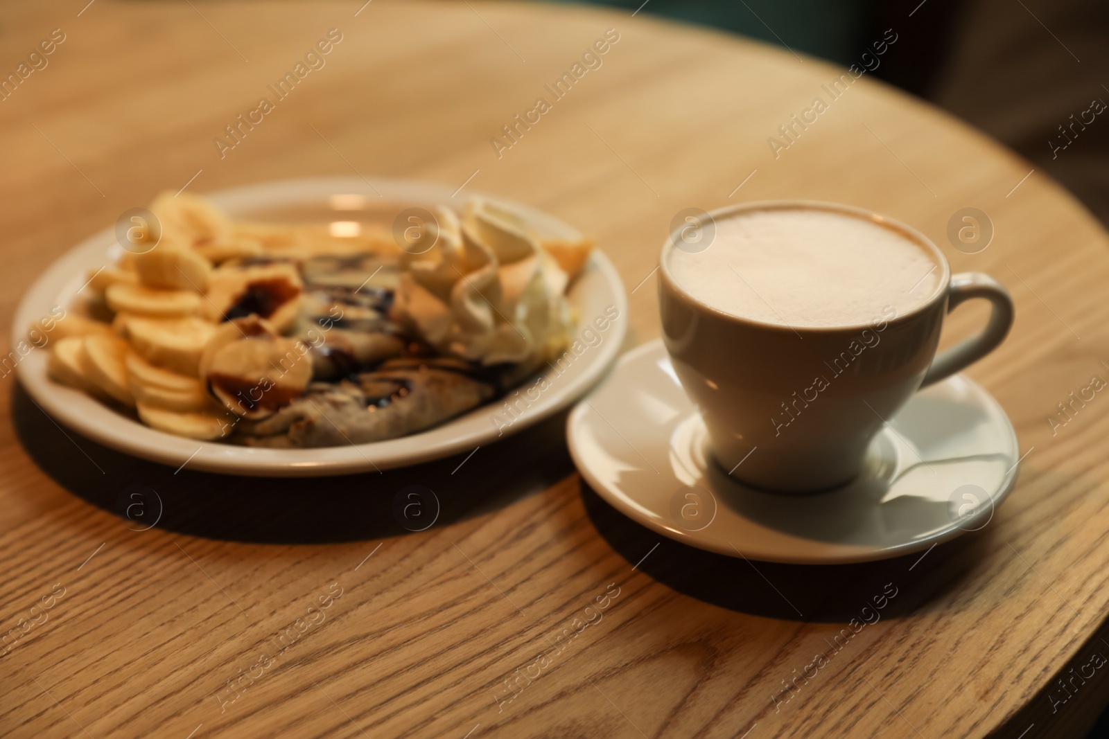 Photo of Cup of aromatic coffee and delicious desserts on wooden table