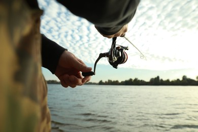 Photo of Fisherman with rod fishing at riverside, closeup