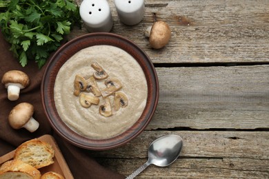 Delicious mushroom cream soup served on wooden table, flat lay. Space for text