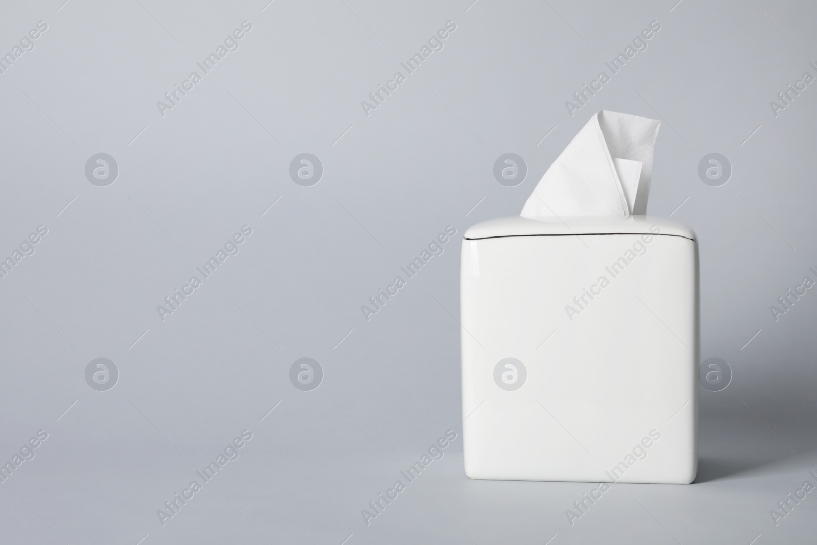 Photo of Napkin holder with paper serviettes on gray background. Space for text