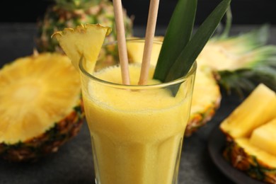 Tasty pineapple smoothie and fruit on table, closeup